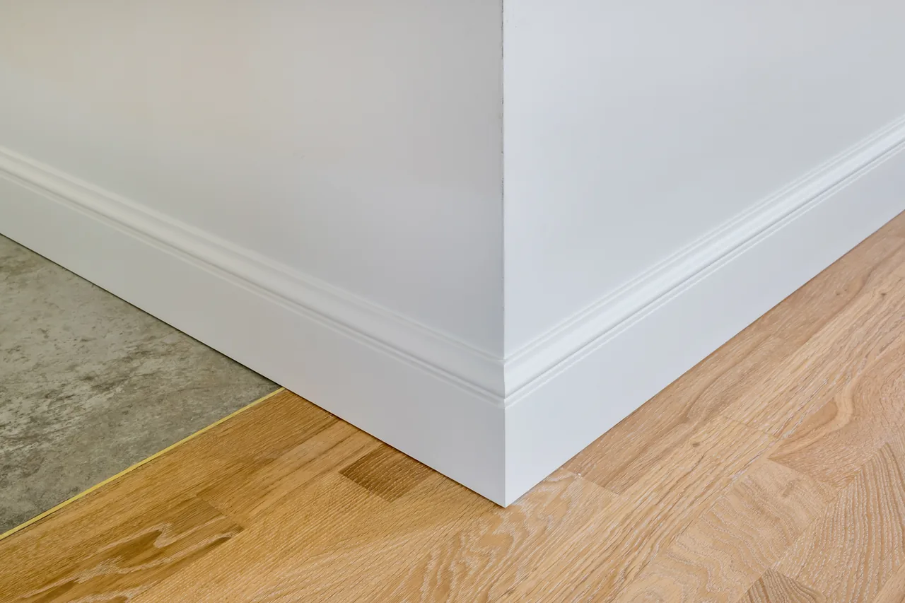 Crisp white baseboards and a clean corner finish. Illustrative stock photo.